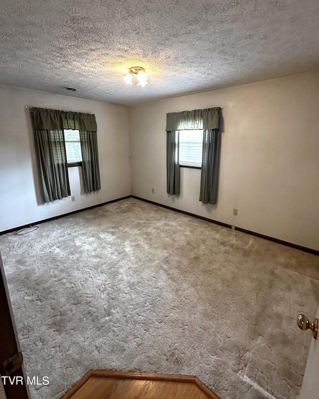 carpeted empty room featuring a textured ceiling