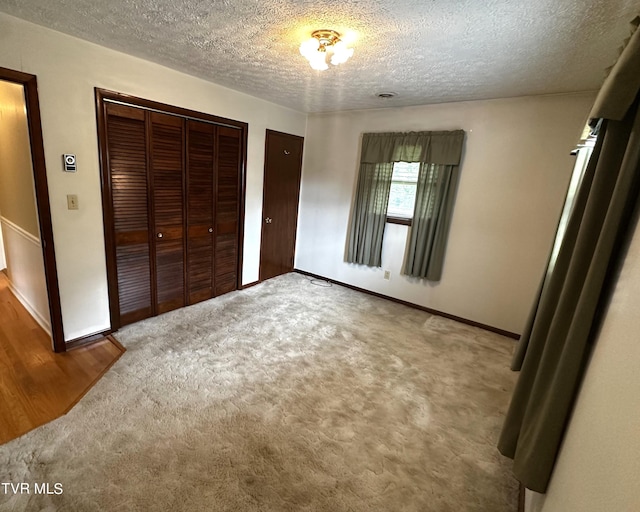 unfurnished bedroom with carpet floors, a textured ceiling, and a closet