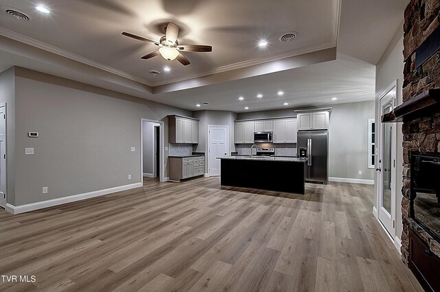 kitchen with backsplash, a center island, light hardwood / wood-style flooring, appliances with stainless steel finishes, and ceiling fan