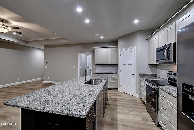 kitchen featuring light hardwood / wood-style flooring, sink, ceiling fan, appliances with stainless steel finishes, and a center island with sink