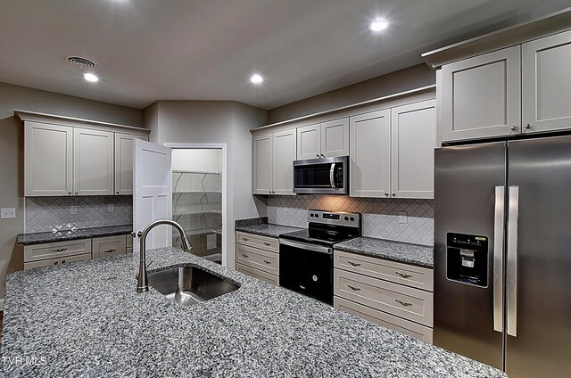 kitchen with backsplash, appliances with stainless steel finishes, stone countertops, sink, and gray cabinets