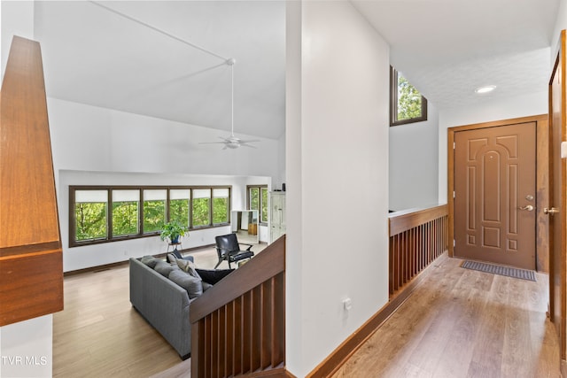 corridor featuring high vaulted ceiling, a wealth of natural light, and light hardwood / wood-style flooring