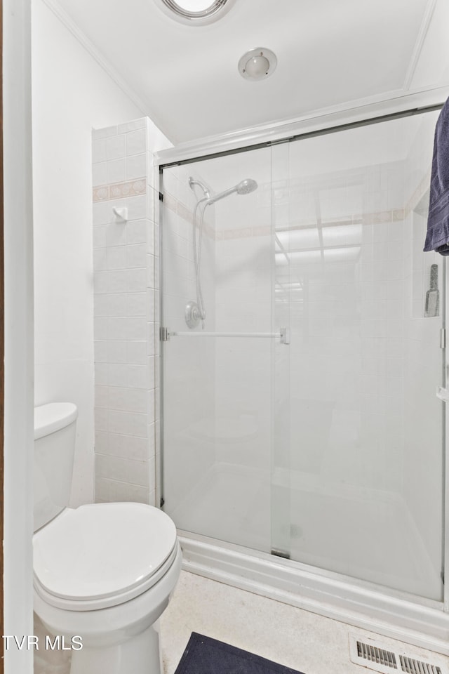 bathroom featuring ornamental molding, an enclosed shower, and toilet