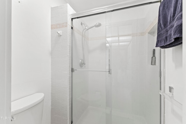 bathroom with a shower with shower door and toilet