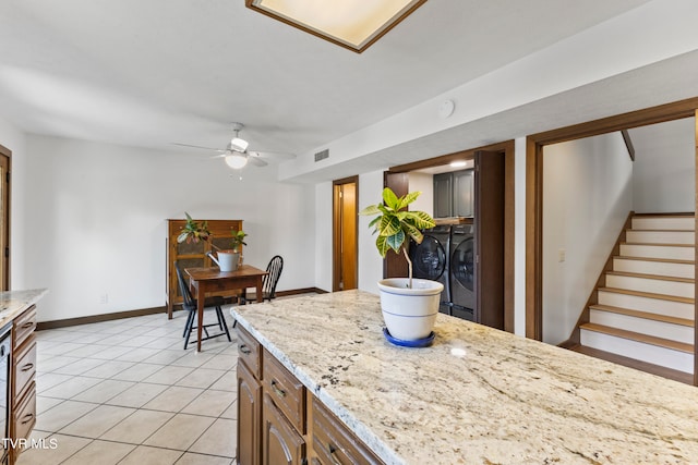 kitchen with washing machine and dryer, ceiling fan, light stone countertops, and light tile patterned flooring