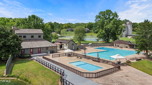 view of pool featuring a patio and a yard