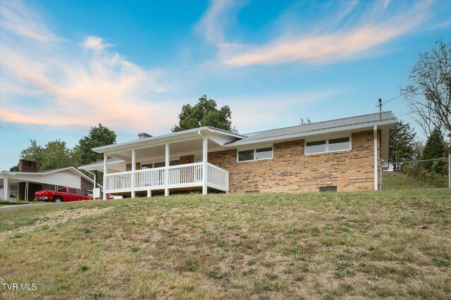 back of house with a lawn and a carport