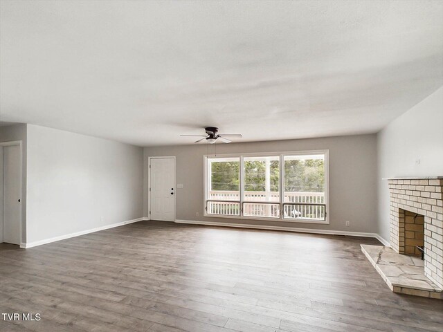 unfurnished living room with a fireplace, ceiling fan, and dark hardwood / wood-style floors