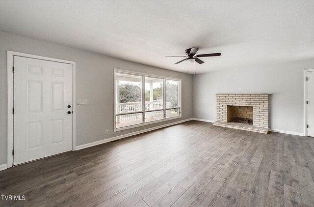 unfurnished living room featuring a fireplace, dark wood-type flooring, and ceiling fan