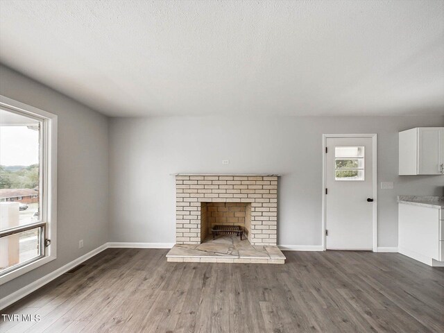 unfurnished living room with a textured ceiling, dark hardwood / wood-style flooring, and a fireplace