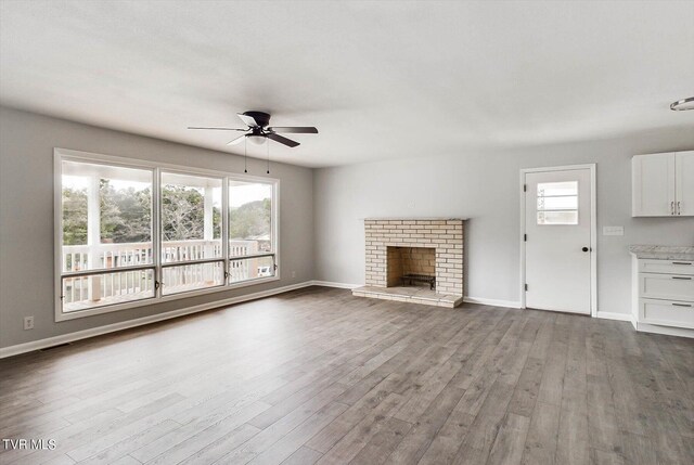 unfurnished living room with ceiling fan, a wealth of natural light, a fireplace, and light hardwood / wood-style floors