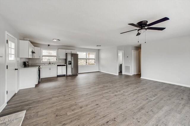 unfurnished living room with wood-type flooring, sink, and ceiling fan