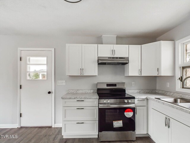 kitchen with a wealth of natural light, stainless steel stove, dark hardwood / wood-style floors, and white cabinetry