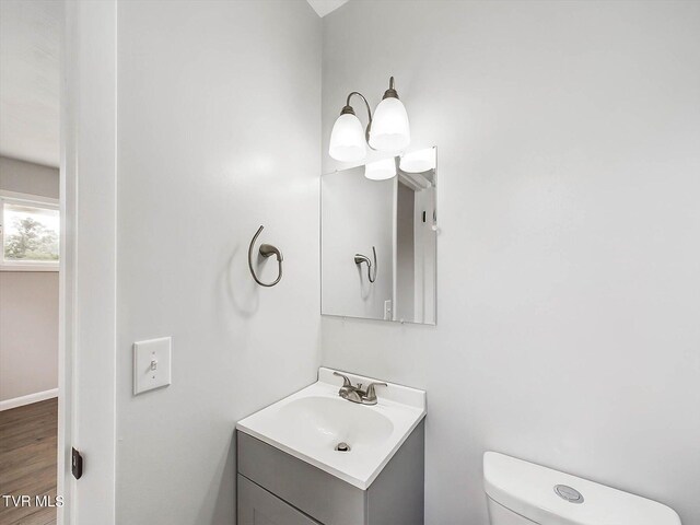 bathroom with vanity, toilet, and hardwood / wood-style floors