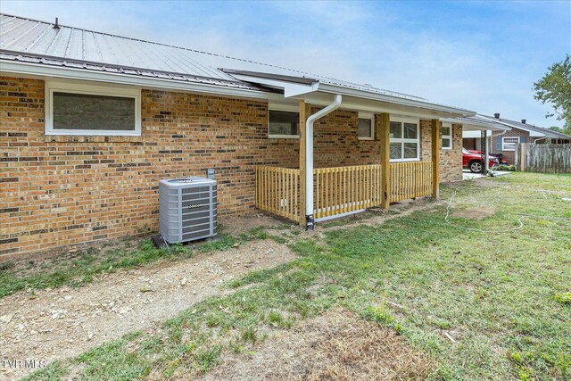 rear view of house with cooling unit and a lawn