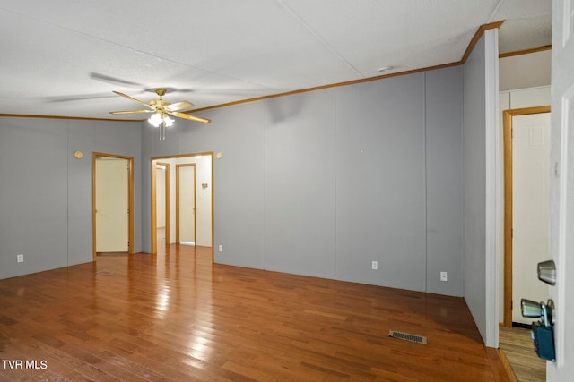 empty room featuring wood-type flooring, a textured ceiling, crown molding, and ceiling fan