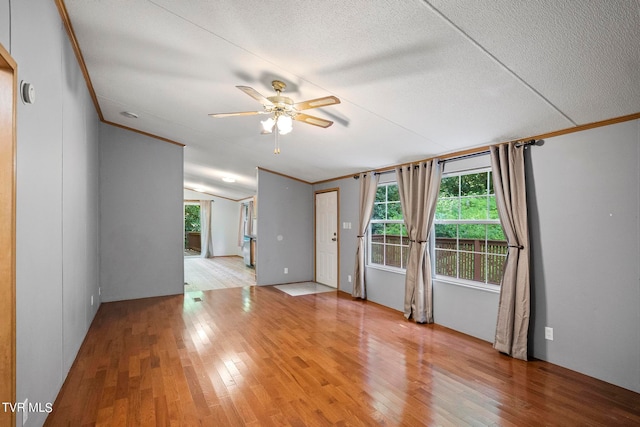 unfurnished room with ornamental molding, a textured ceiling, ceiling fan, vaulted ceiling, and hardwood / wood-style flooring