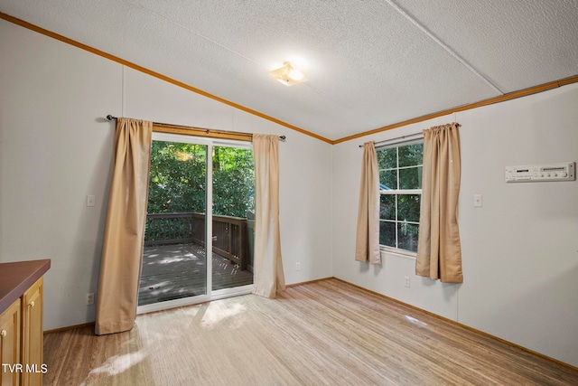 empty room featuring light wood-type flooring, vaulted ceiling, and a textured ceiling