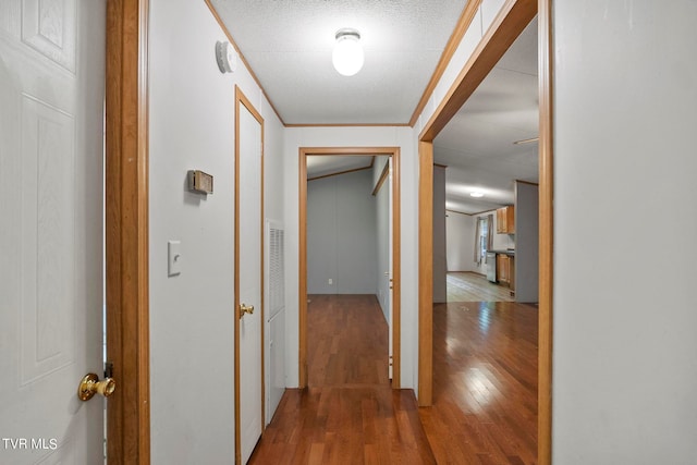 hall with hardwood / wood-style floors, ornamental molding, and a textured ceiling