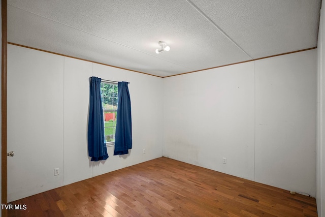 spare room with ornamental molding, a textured ceiling, and hardwood / wood-style flooring