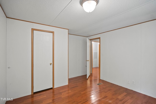 interior space with ornamental molding, a textured ceiling, and wood-type flooring