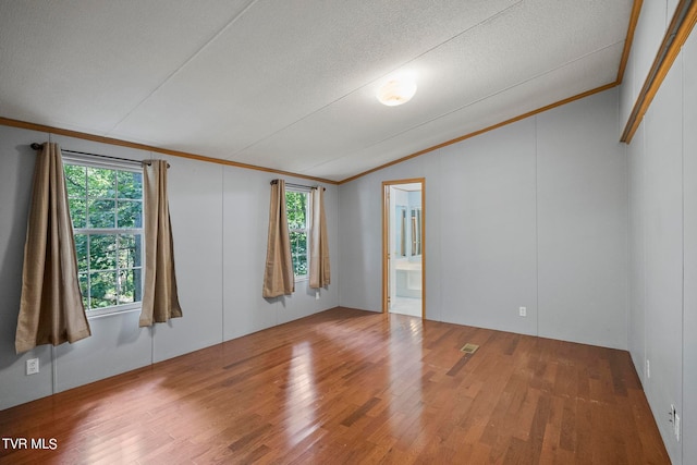 spare room featuring wood-type flooring, plenty of natural light, ornamental molding, and vaulted ceiling