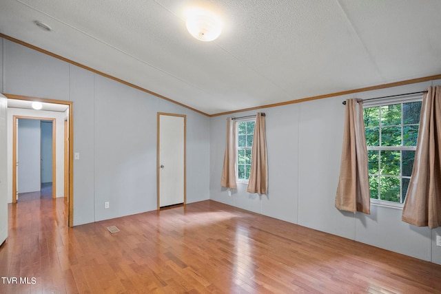 unfurnished room with crown molding, a healthy amount of sunlight, vaulted ceiling, and hardwood / wood-style flooring