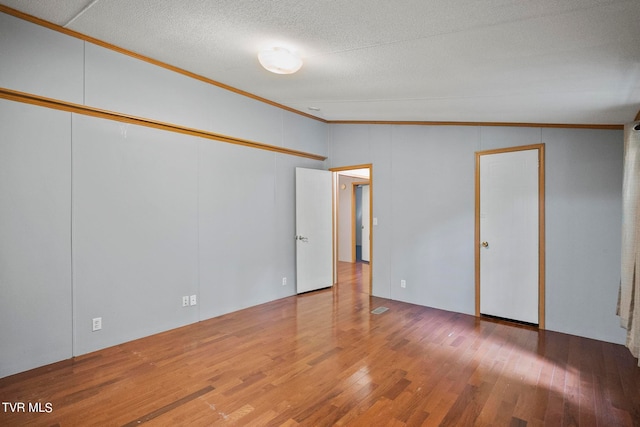 unfurnished room featuring crown molding, vaulted ceiling, and hardwood / wood-style floors