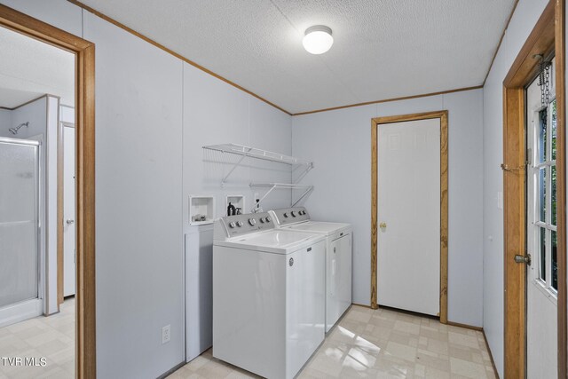 washroom with ornamental molding, a textured ceiling, and independent washer and dryer