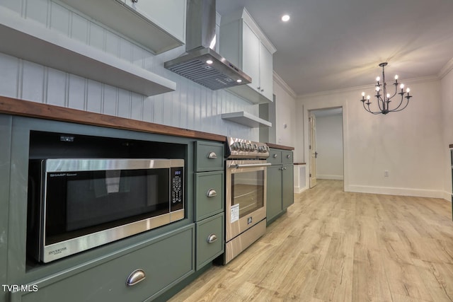 kitchen with a notable chandelier, stainless steel appliances, wall chimney range hood, white cabinets, and light hardwood / wood-style floors