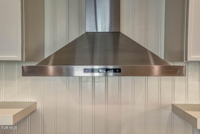 interior details with wall chimney exhaust hood and white cabinets