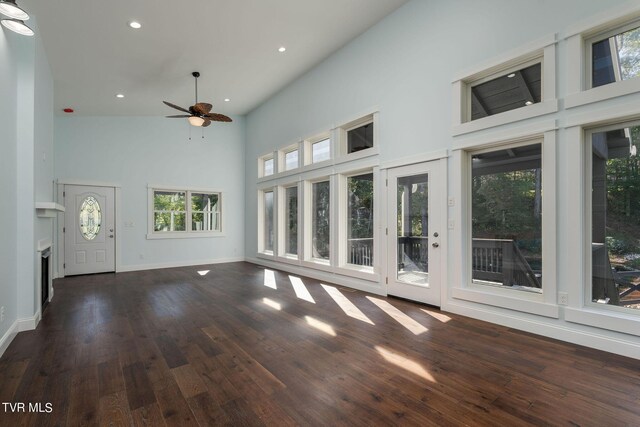 unfurnished living room with plenty of natural light, dark hardwood / wood-style floors, and high vaulted ceiling