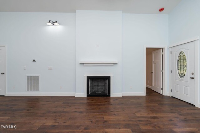 unfurnished living room with a towering ceiling and dark hardwood / wood-style floors