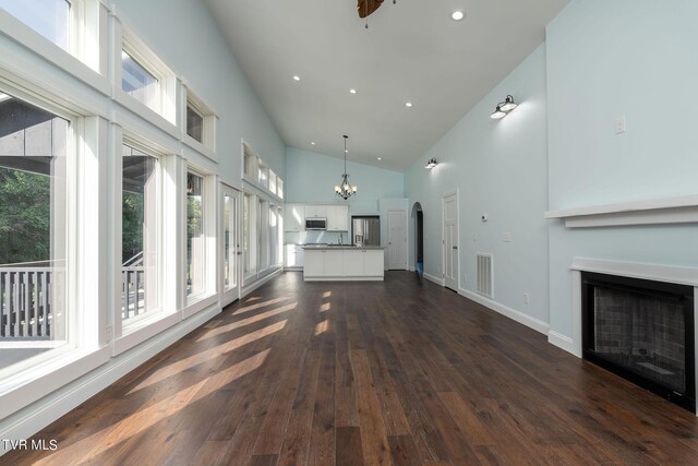 unfurnished living room featuring high vaulted ceiling, a notable chandelier, sink, and dark hardwood / wood-style flooring