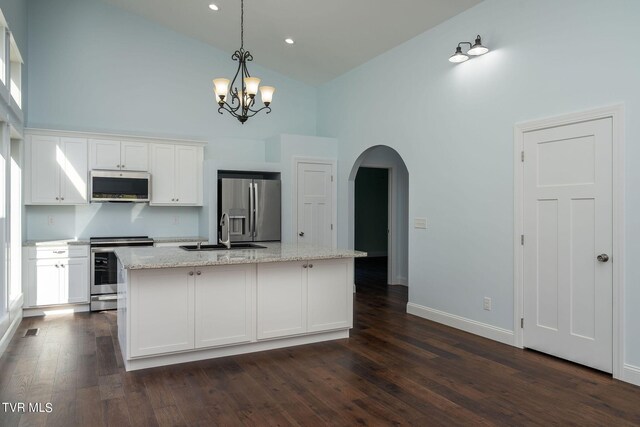 kitchen featuring high vaulted ceiling, stainless steel appliances, an island with sink, and white cabinetry