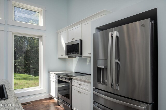 kitchen with light stone countertops, a wealth of natural light, and appliances with stainless steel finishes