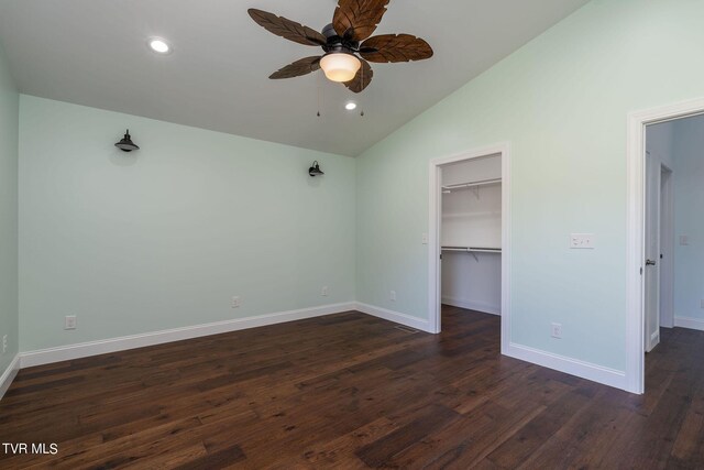 unfurnished bedroom featuring a closet, vaulted ceiling, a walk in closet, dark hardwood / wood-style flooring, and ceiling fan