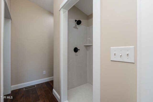 bathroom with hardwood / wood-style floors and a tile shower