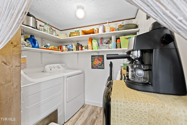 clothes washing area with washer and dryer, light wood-type flooring, and a textured ceiling