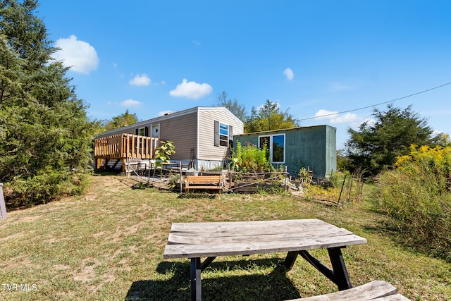 rear view of house featuring a lawn and a wooden deck