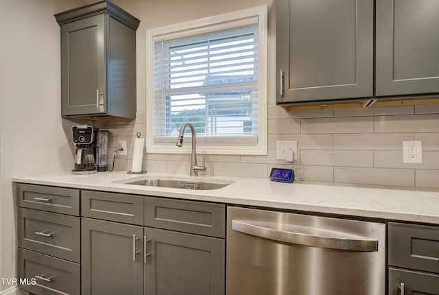 kitchen with sink, tasteful backsplash, dishwasher, gray cabinets, and light stone countertops