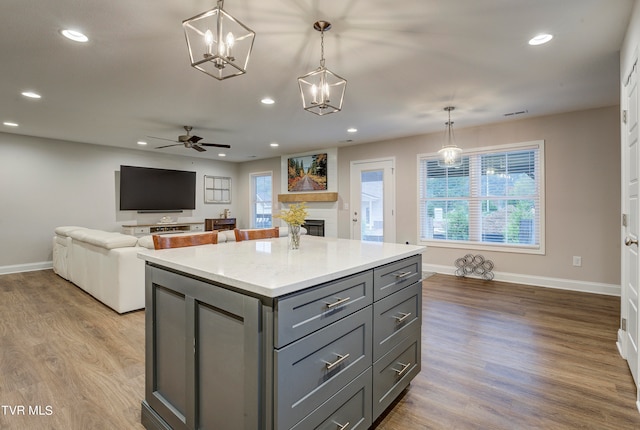 kitchen with light wood-type flooring, a fireplace, gray cabinets, and decorative light fixtures