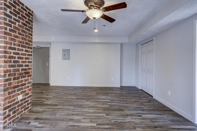 empty room with dark wood-type flooring, a textured ceiling, electric panel, and ceiling fan