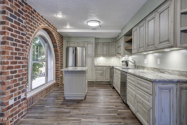 kitchen featuring stainless steel appliances, dark hardwood / wood-style flooring, sink, a kitchen island, and a textured ceiling