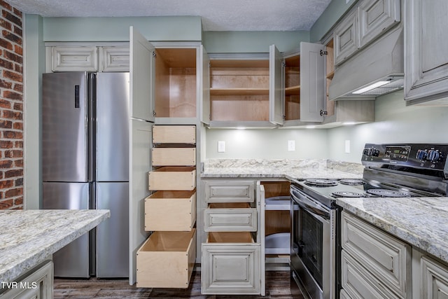 kitchen featuring custom range hood, appliances with stainless steel finishes, light stone counters, dark wood-type flooring, and a textured ceiling