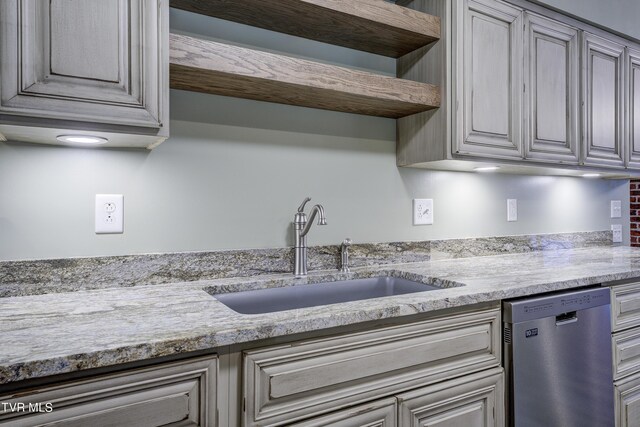 kitchen featuring light stone countertops, sink, and stainless steel dishwasher