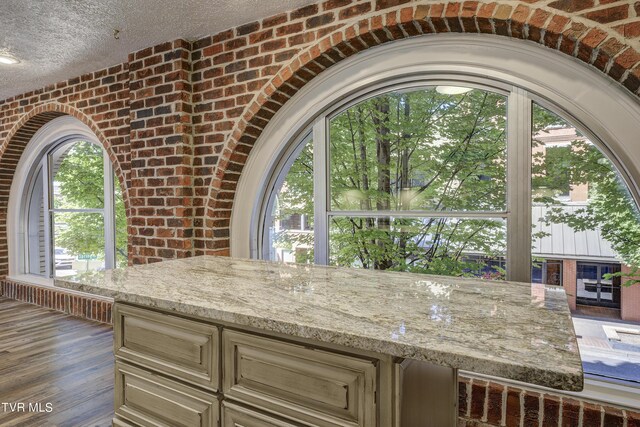 kitchen with cream cabinetry, light stone countertops, and dark wood-type flooring