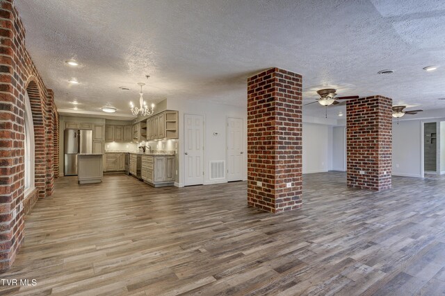 unfurnished living room with ceiling fan with notable chandelier, a textured ceiling, and wood-type flooring