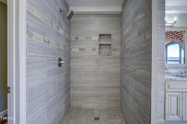 bathroom featuring tiled shower, vanity, and a textured ceiling