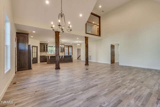 unfurnished living room with high vaulted ceiling and light wood-type flooring